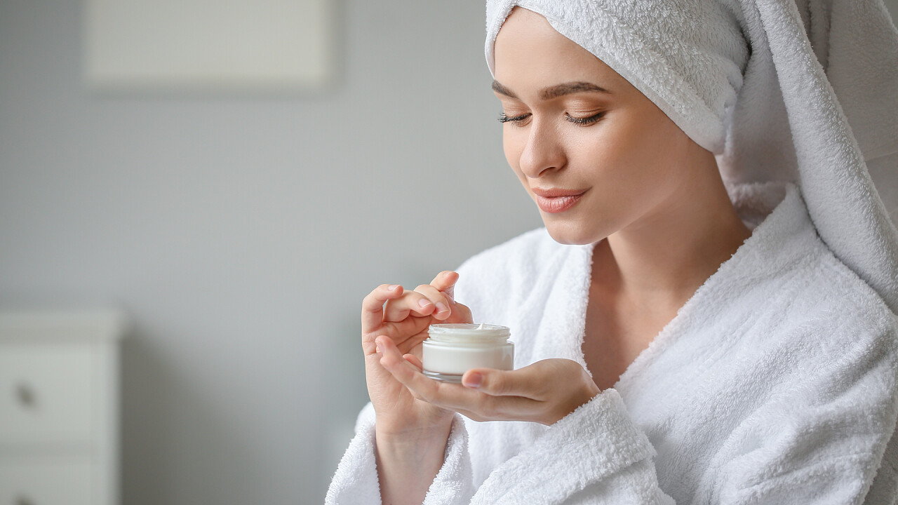 Woman in bathrobe with cream in her hands